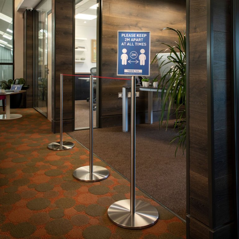 Absolute Freestanding Barriers in an office environment adapted to carry information signage about social distancing.